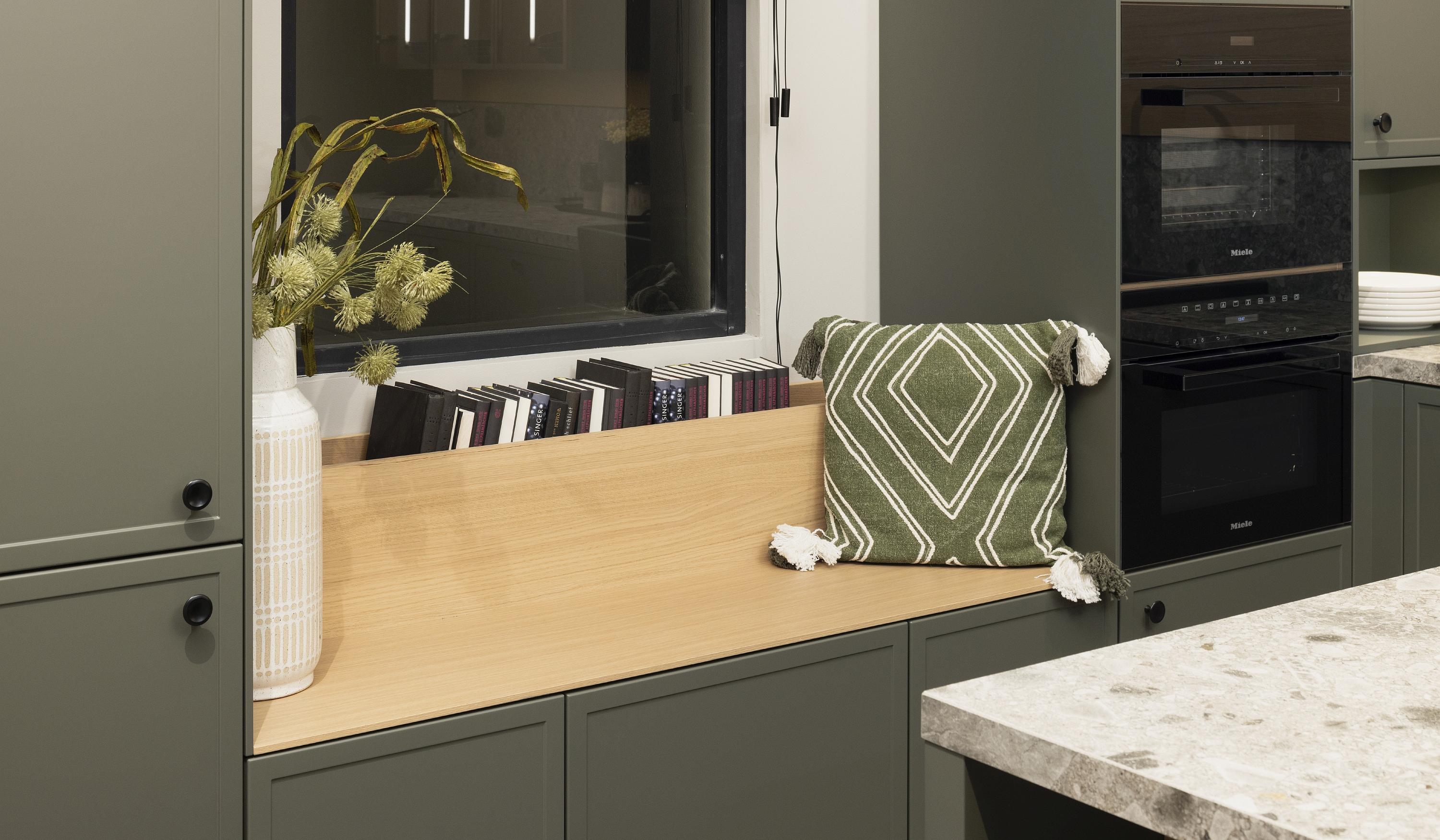 Sitznische aus hellem Holz in einer dunkelgrauen modernen Landhausküche von Häcker